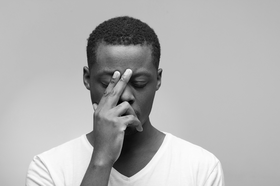 Thoughtful young african american man with closed eyes on grey background with free space for text.